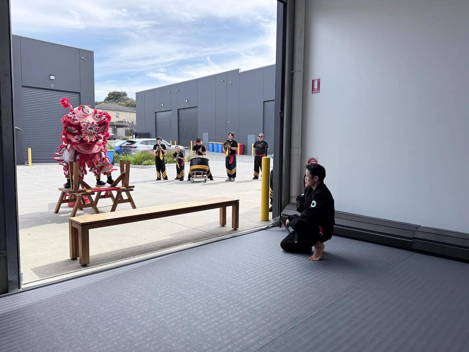 The lion dance troupe performing in the car park outside the academy