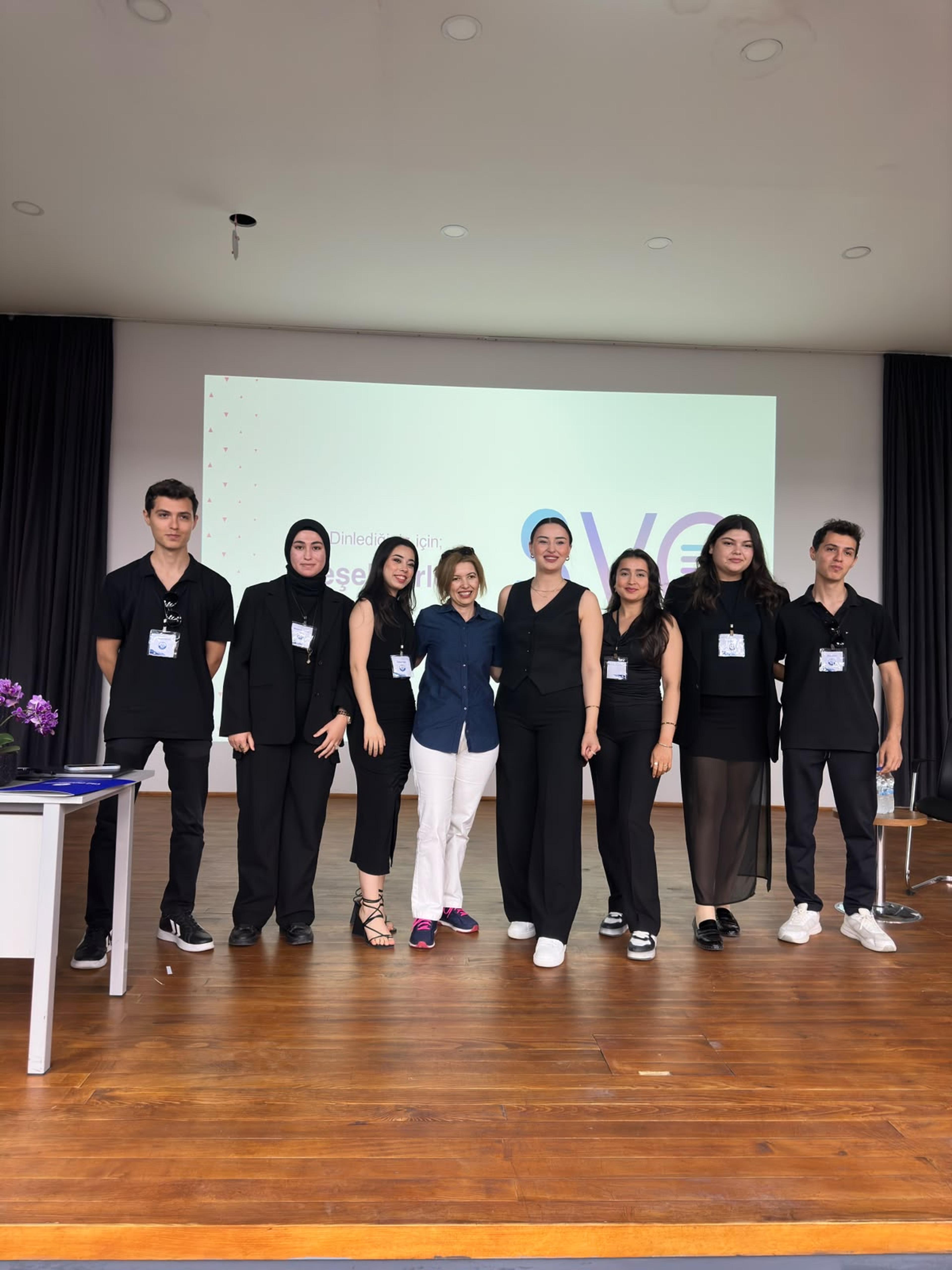 Sahnede sunum sonrası grup fotoğrafı; arkadaki ekranda SVO logosu