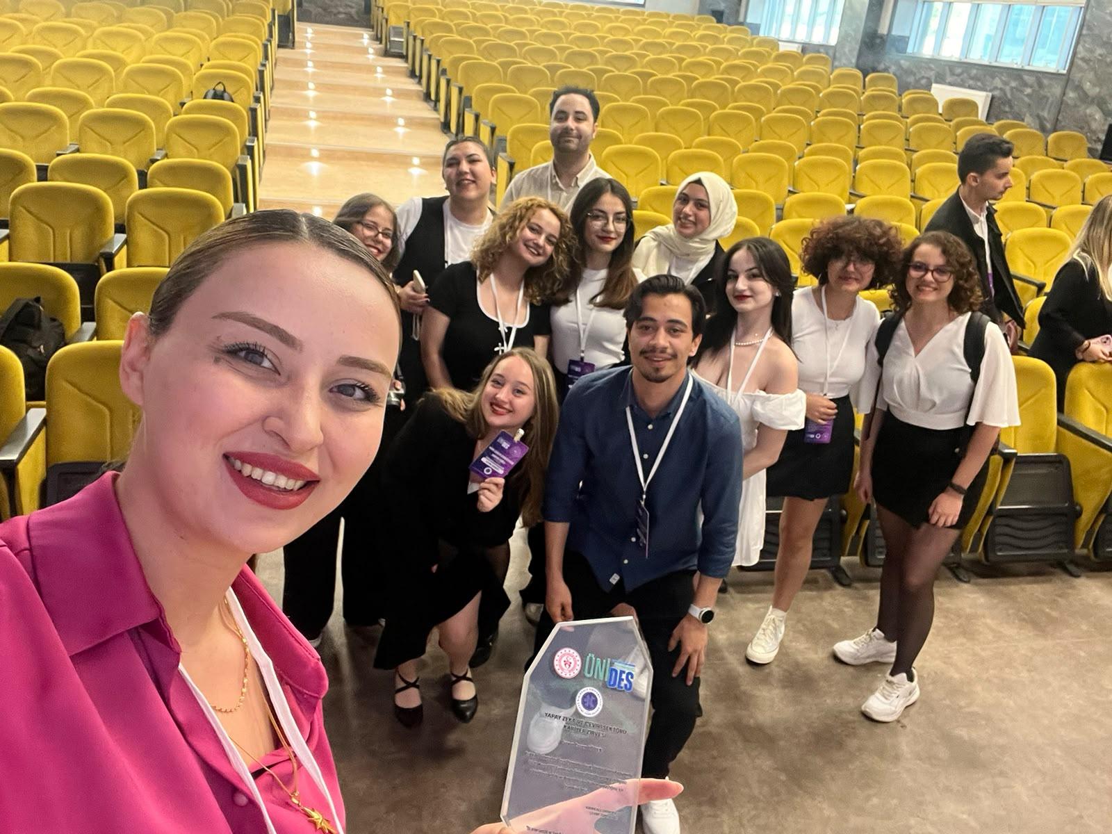 Ceren Höbek, konferans salonunda çeviri öğrencileriyle; elinde zirve plaketi