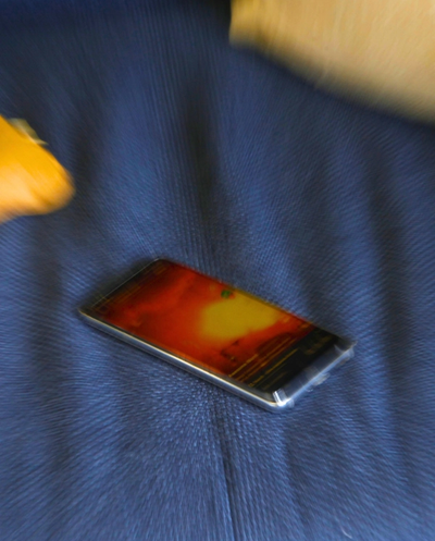 A smartphone with a vibrant red and yellow screen lies on a blurred blue textured surface.