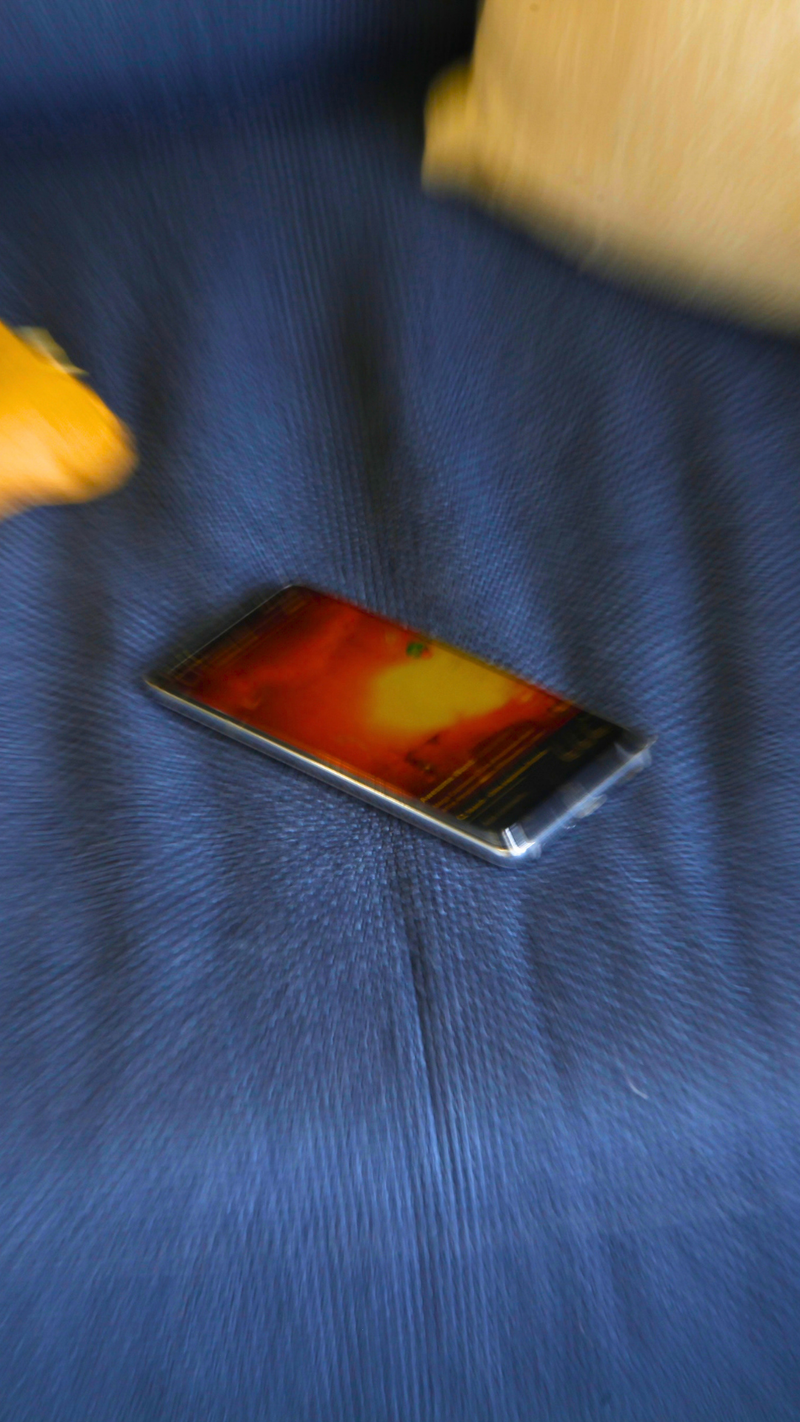 A smartphone with a vibrant orange and yellow display rests on a blue textured surface.