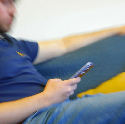 A person, heavily blurred with radial motion, is sitting in a blue shirt and jeans, holding a smartphone.