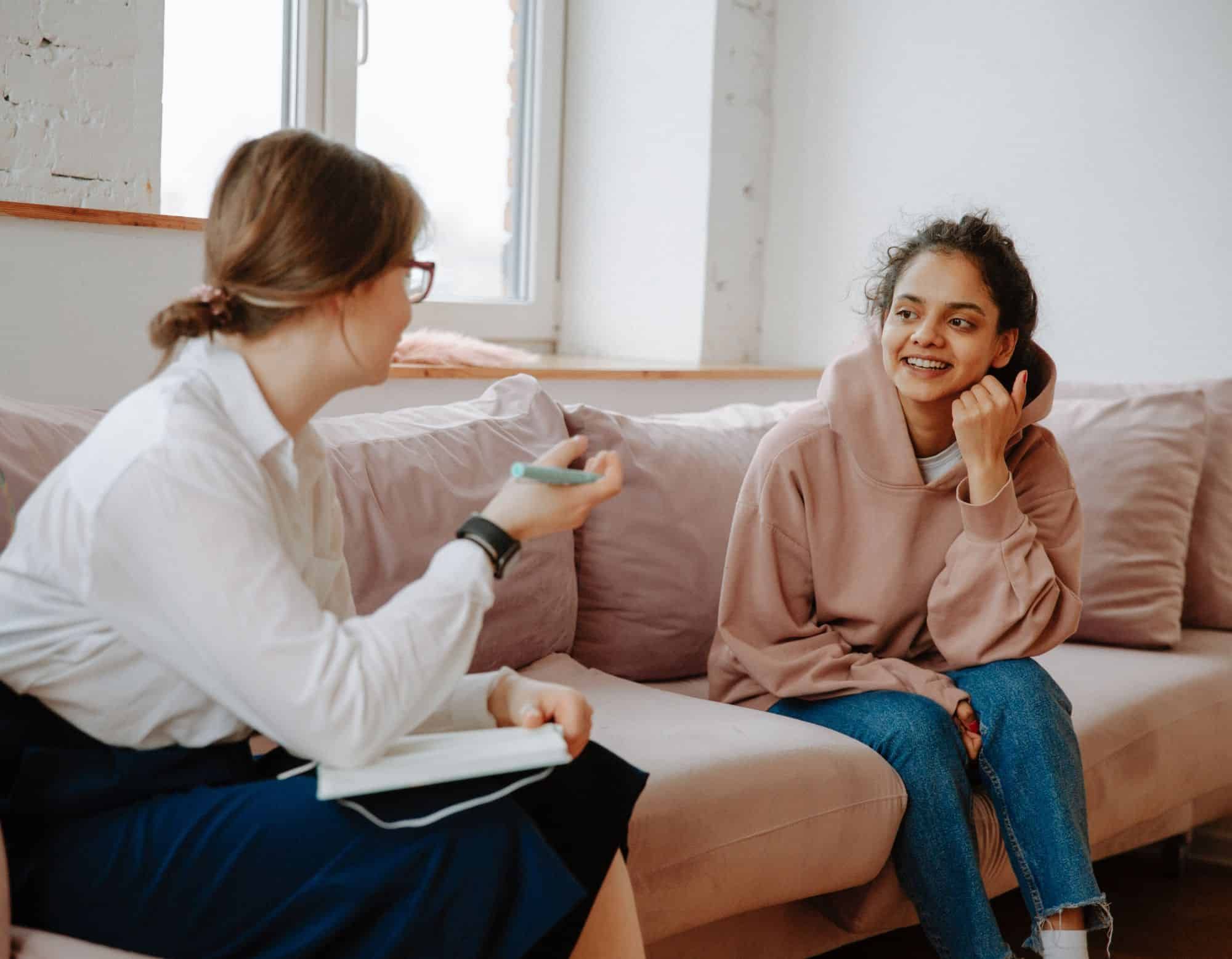 Teen and therapist mid-conversation in a modern, calm office — warm natural light, unposed body language