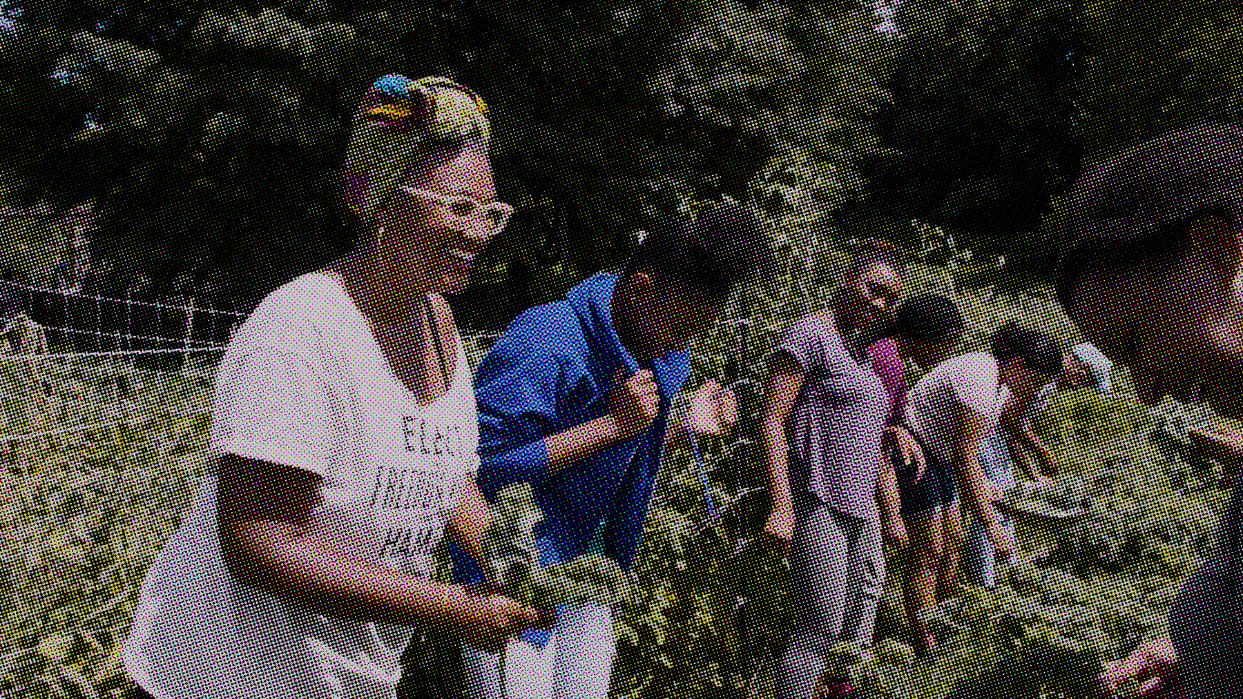 Shivon Love, a Black woman wearing a white T-shirt and white glasses, gathers kale in a lush garden alongside a group of young cooking camp participants.