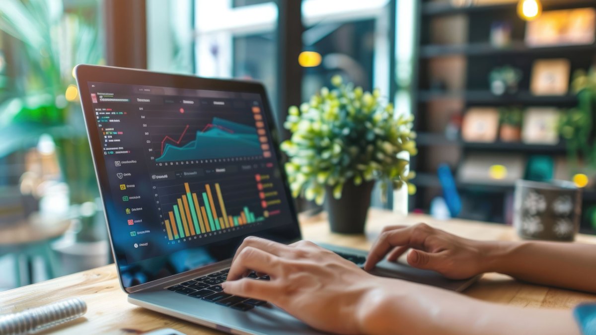 Person typing on a laptop displaying data charts and graphs.