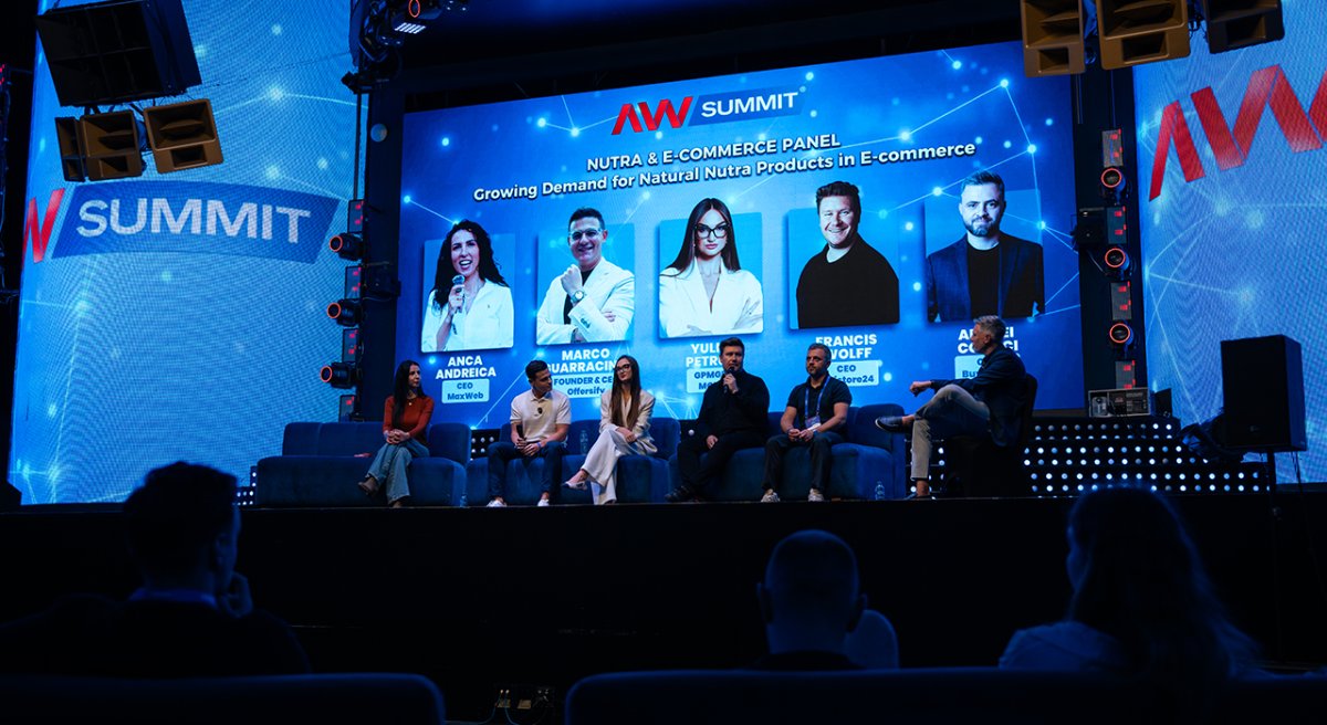 Six panelists sit on a stage under a large screen displaying 'Nutra & E-commerce Panel' and speaker images at the AW Summit.