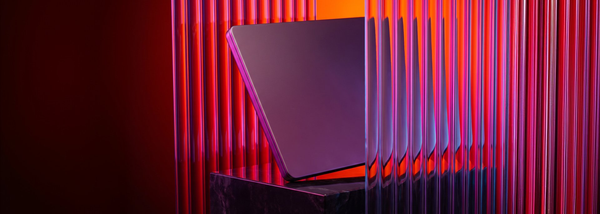 Dark rectangular device on a black pedestal, framed by vertical translucent rods with red and purple lighting.