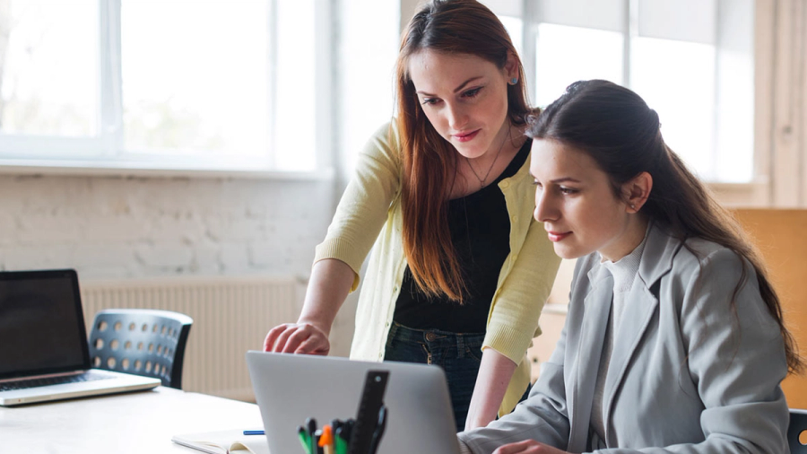 Two women collaborating on a laptop.