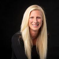 Smiling woman with long blonde hair against a black background.