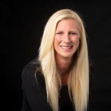 Smiling woman with long blonde hair against a black background.