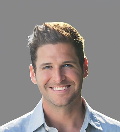Headshot of a smiling man with light brown hair and blue eyes, wearing a light blue shirt.