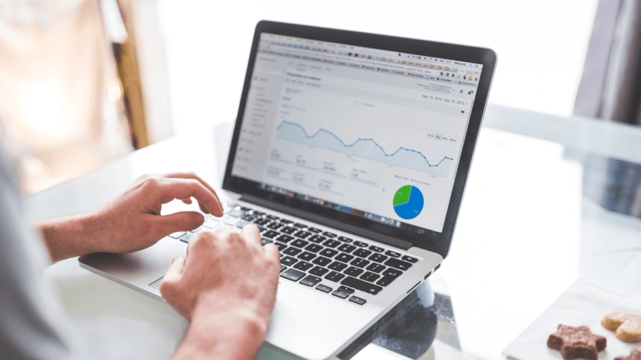 Person typing on a laptop displaying data analytics charts and graphs.