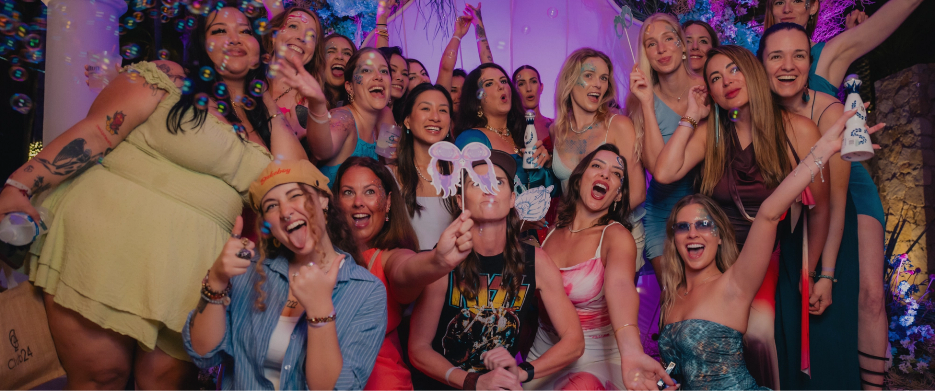 A large group of women smiling and celebrating at a vibrant party.