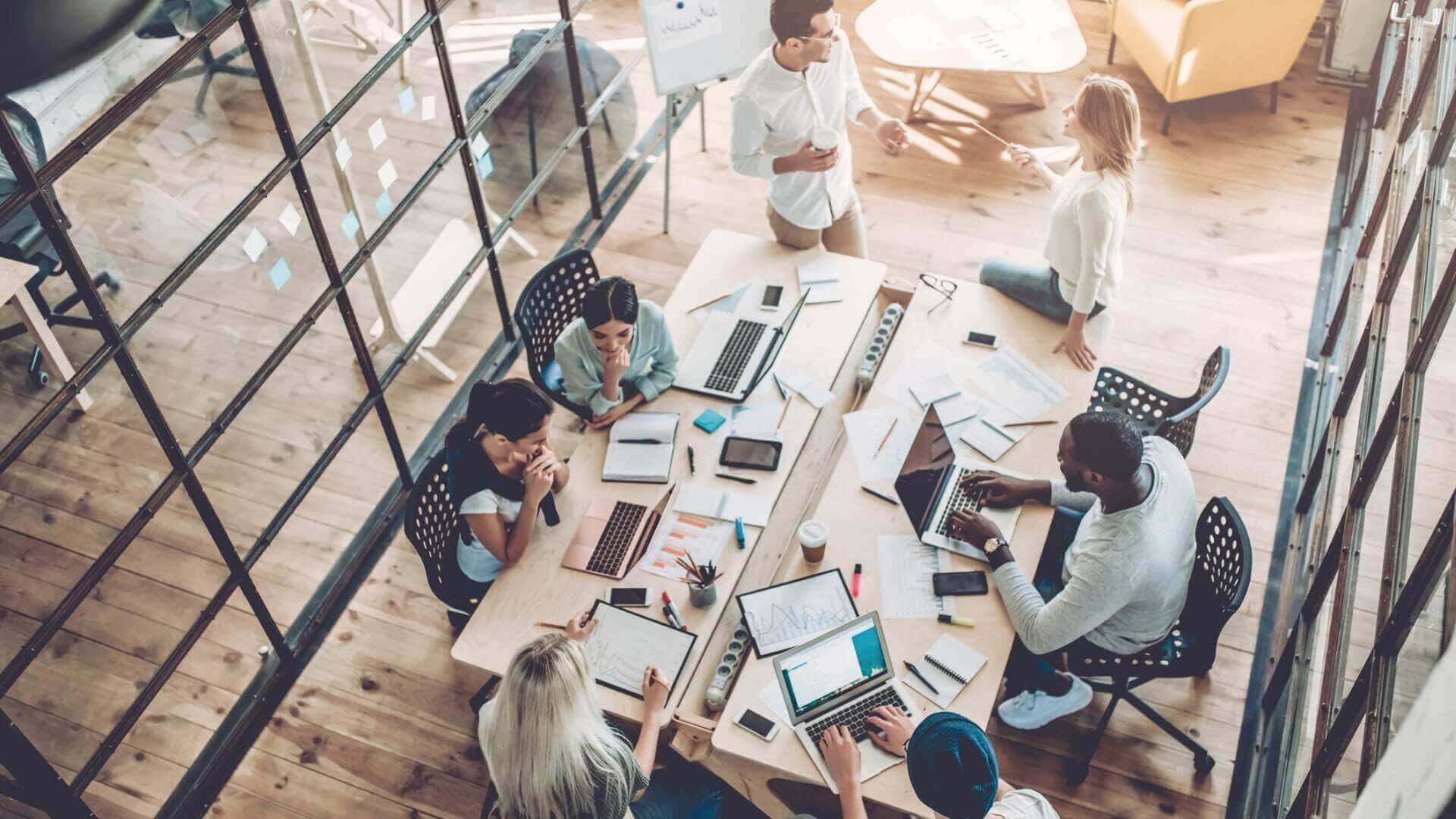 Overhead view of a diverse team collaborating in a modern open-plan office.