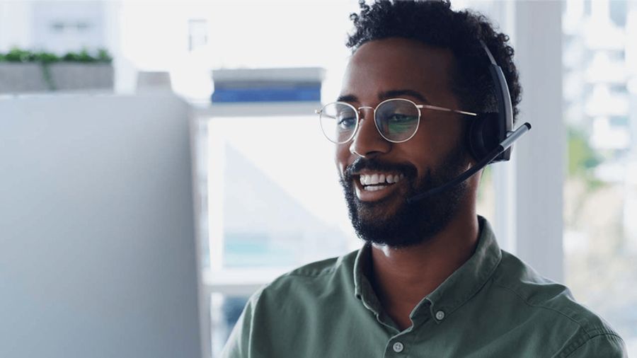 Smiling Black man with glasses wearing a headset.