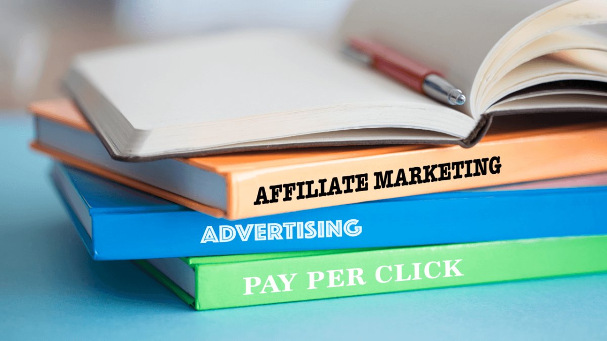 A stack of books with spines reading "Affiliate Marketing," "Advertising," and "Pay Per Click," topped with an open book and pen.