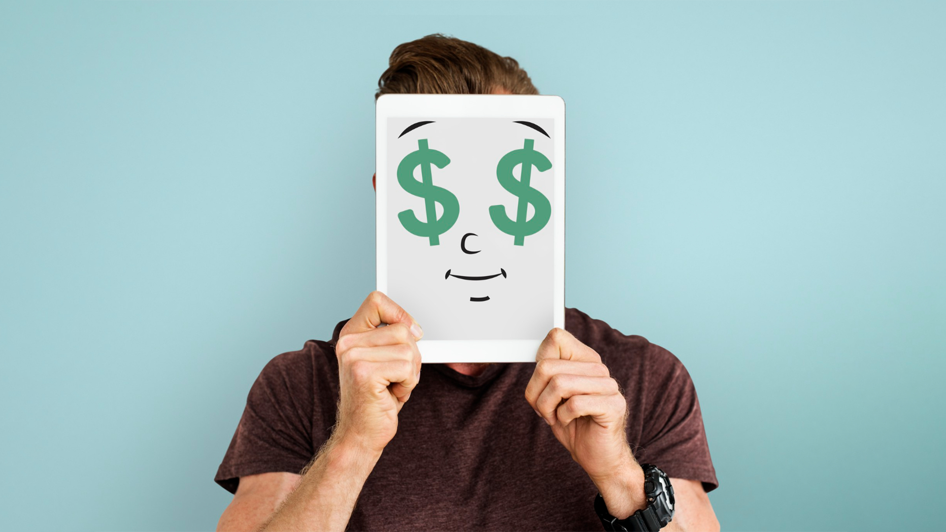 A person holds a tablet with a cartoon face showing dollar signs for eyes.