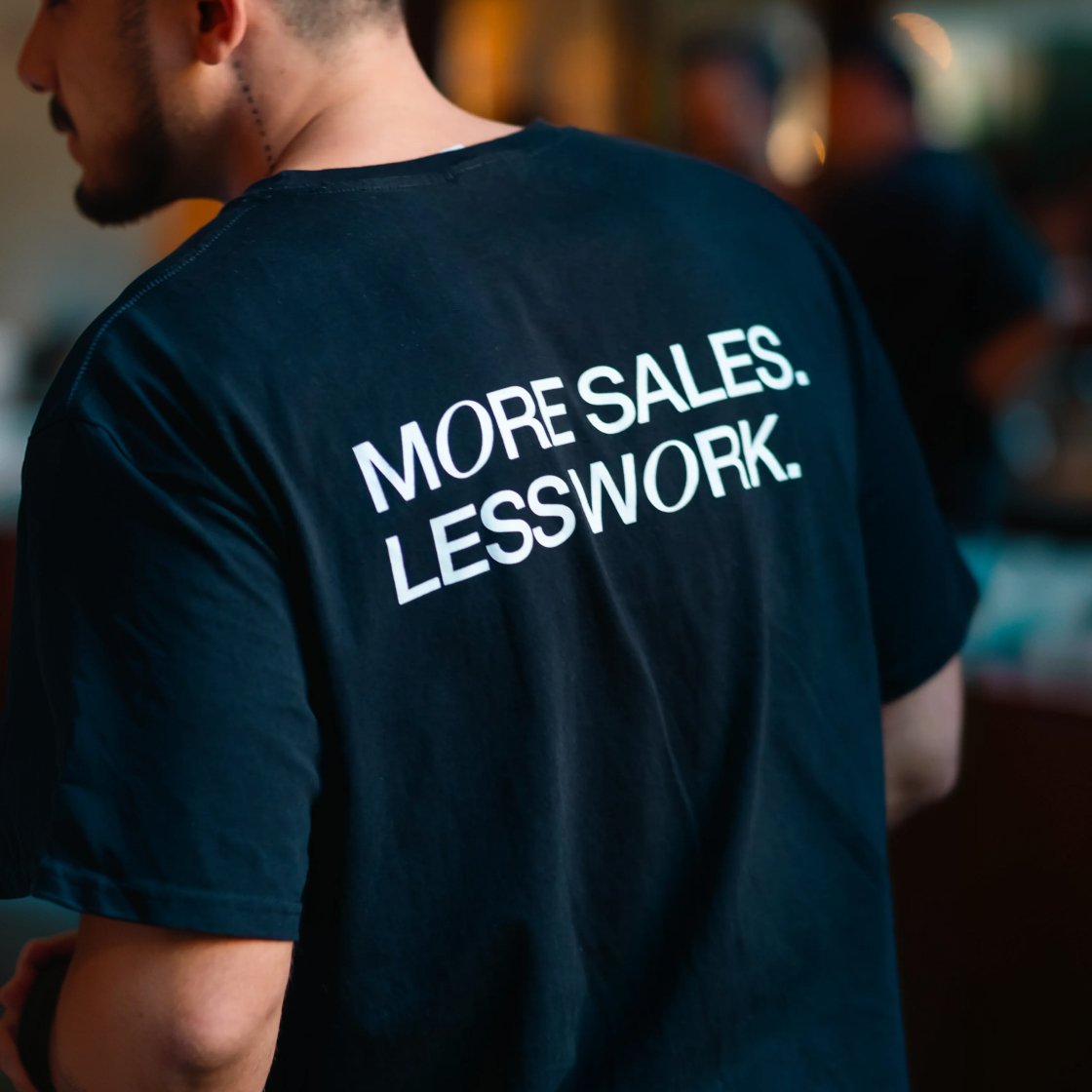 "More sales, less work" shirt at an event