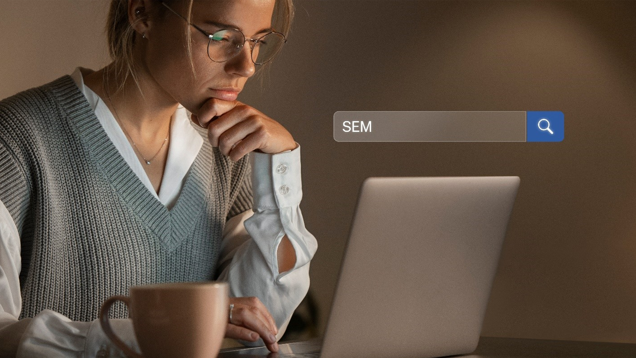 A woman looks thoughtfully at her laptop with a search bar showing "SEM" above it.