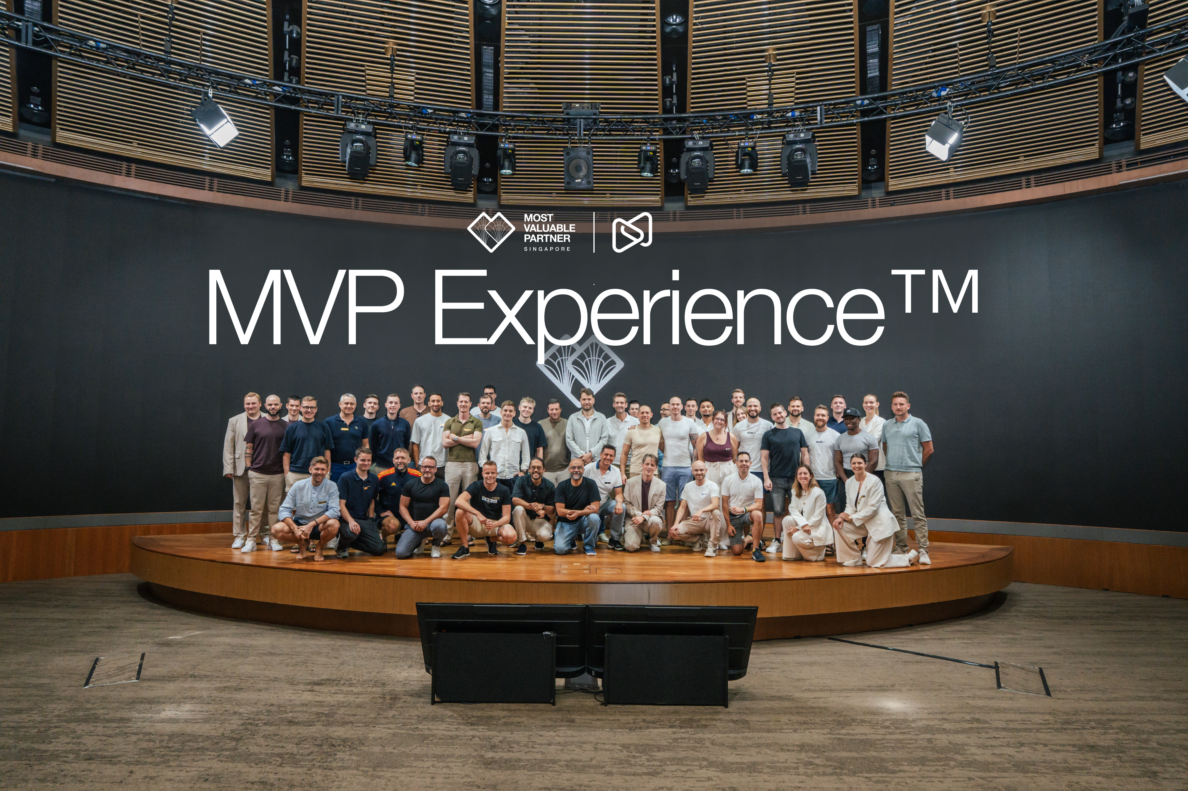 A large group of people poses on a stage in front of a screen displaying "MVP Experience" and company logos.