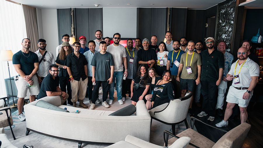 A diverse group of people, many wearing lanyards, smile in a modern lounge.