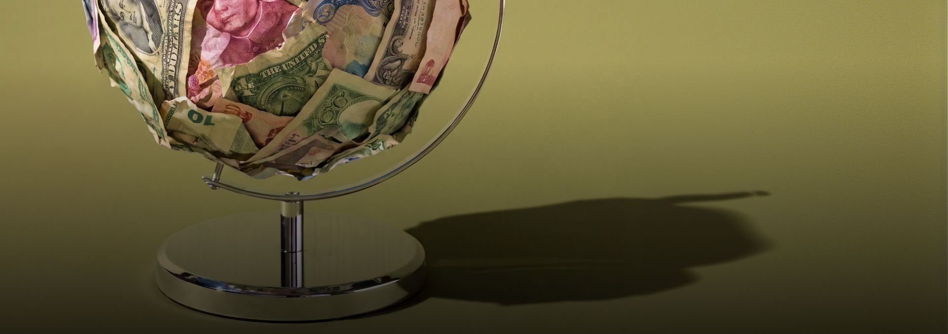 Globe made of banknotes on an olive background.