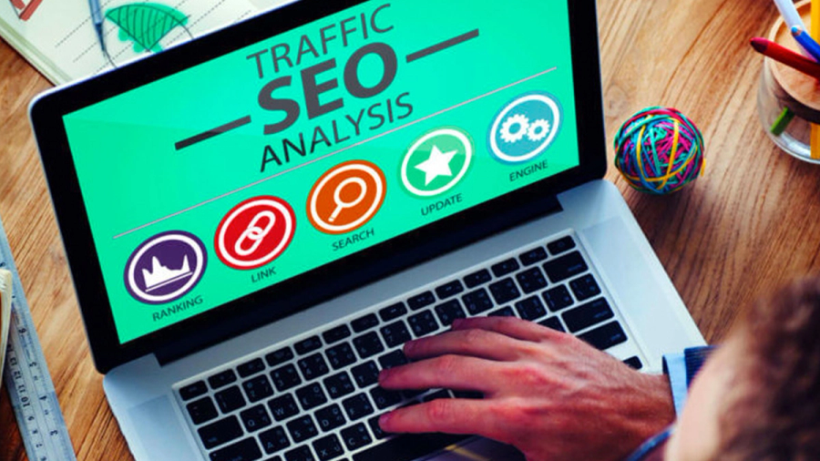 A person types on a laptop displaying "Traffic SEO Analysis" and related icons.