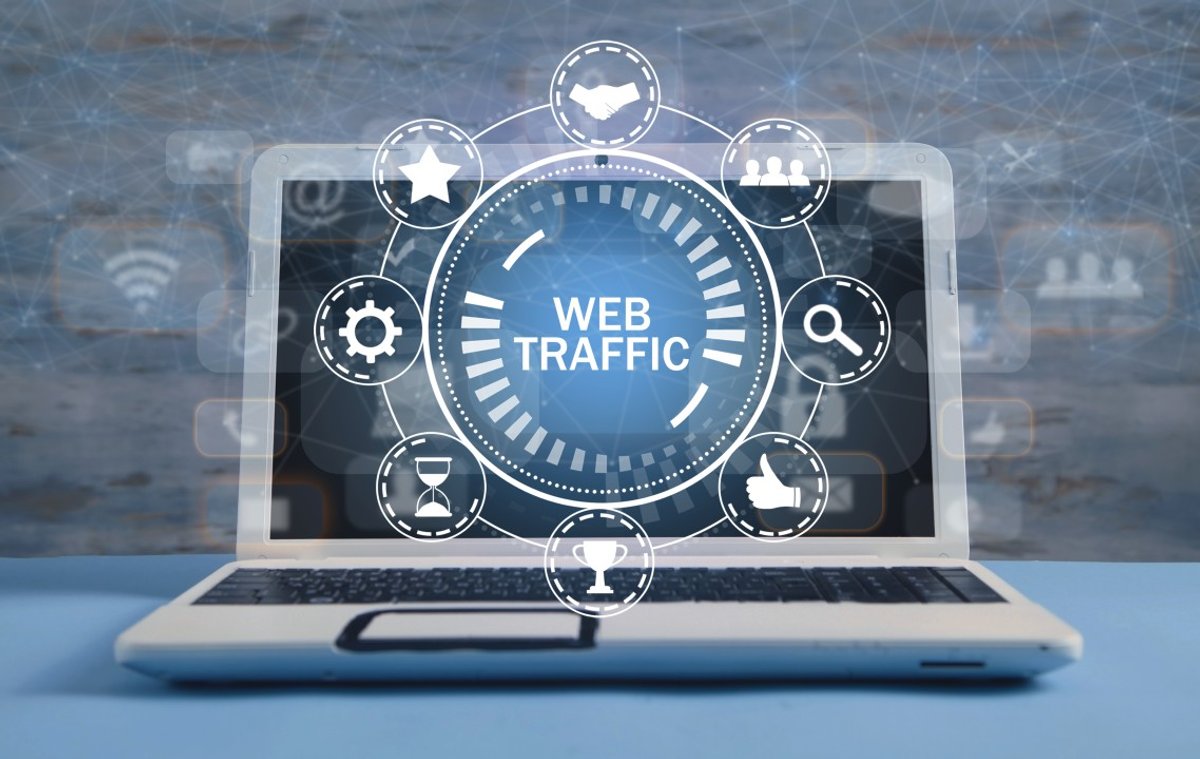 A laptop displaying a holographic "WEB TRAFFIC" interface surrounded by various digital marketing and analytics icons.