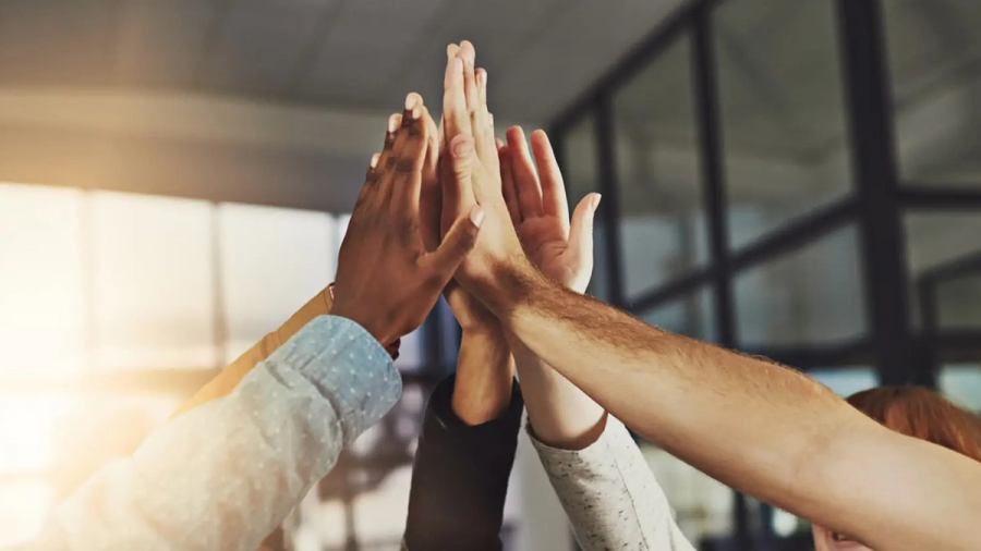 Diverse hands stacked in a high-five gesture.