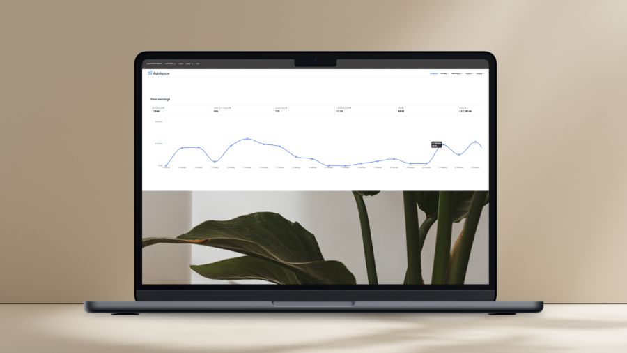 A laptop on a desk displays an earnings graph and a plant wallpaper, with a real plant in the background.