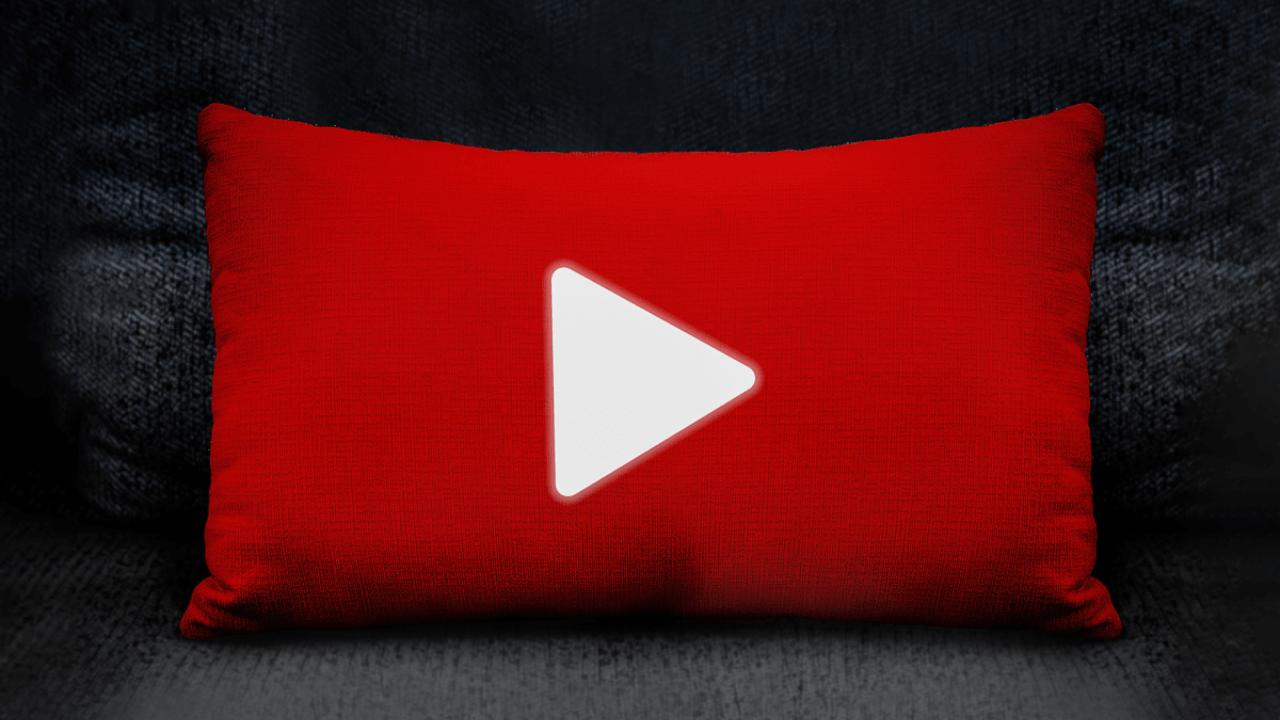 A red pillow with the white YouTube play button logo sits on a dark textured surface.