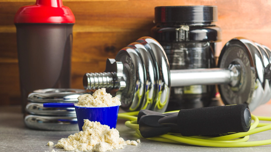 Protein powder, a shaker bottle, dumbbell, and jump rope.