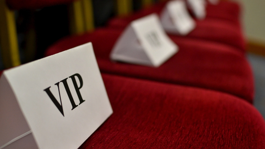 A white "VIP" sign on a red velvet seat in a row.