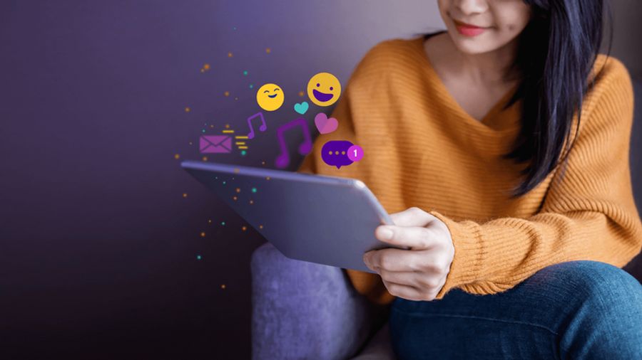 Woman holding a tablet with social media and content icons floating above.