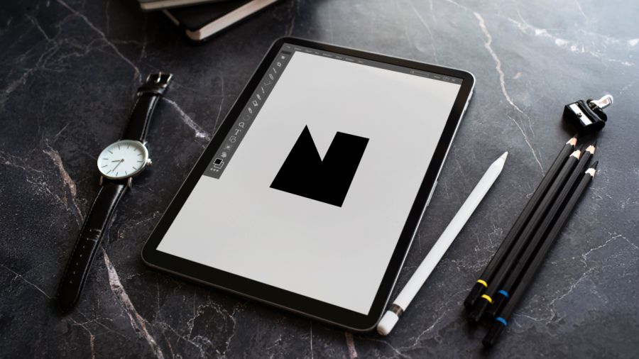 Tablet displaying a black 'M' design, Apple Pencil, watch, and pencils on a dark marble desk.
