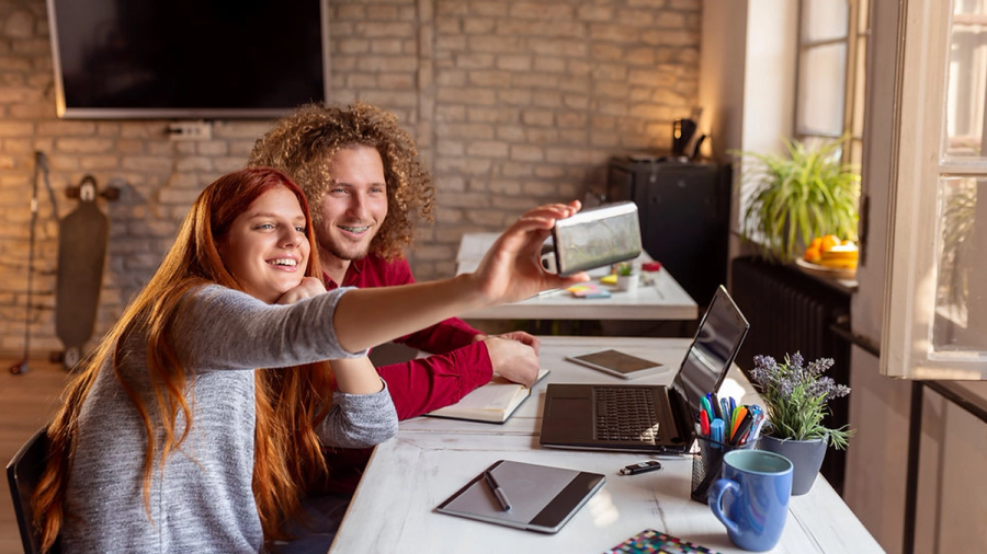 Two young people taking a selfie at a desk.