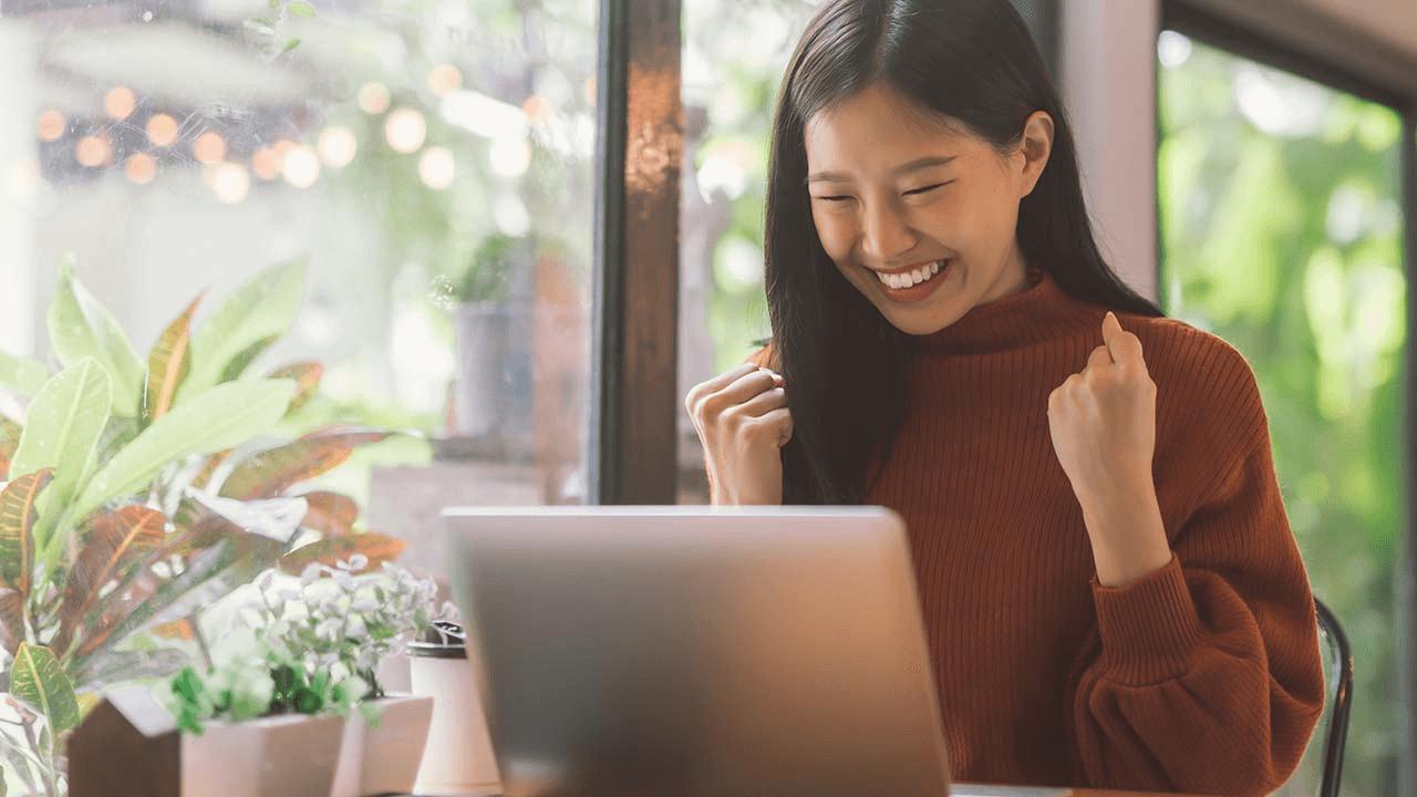 Young Asian woman smiling and looking happy at her increased AOV.