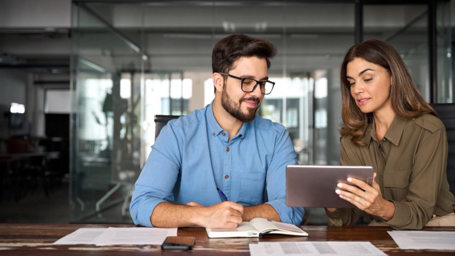 Two colleagues reviewing a tablet and taking notes.
