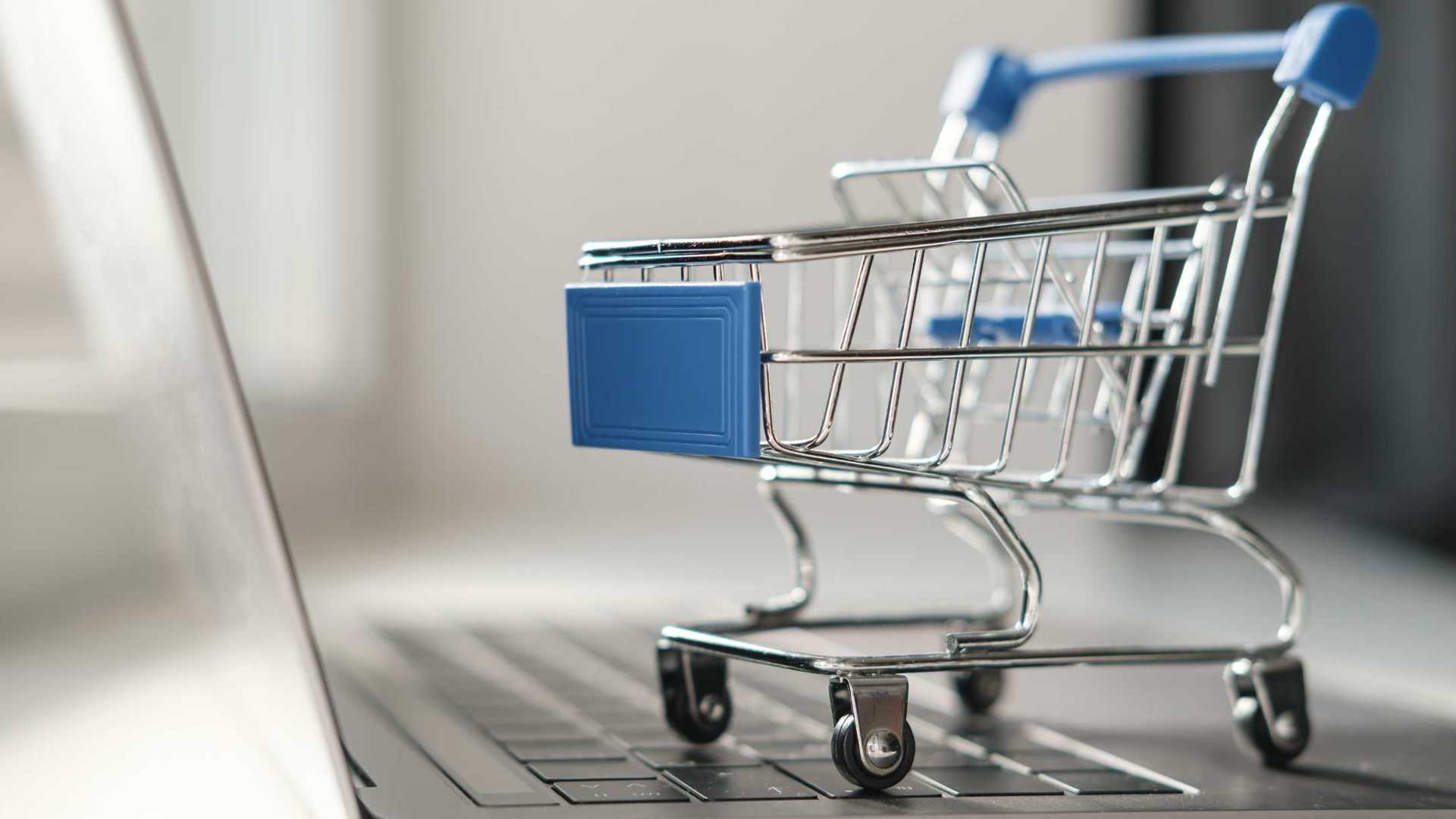 Miniature shopping cart on a laptop keyboard.