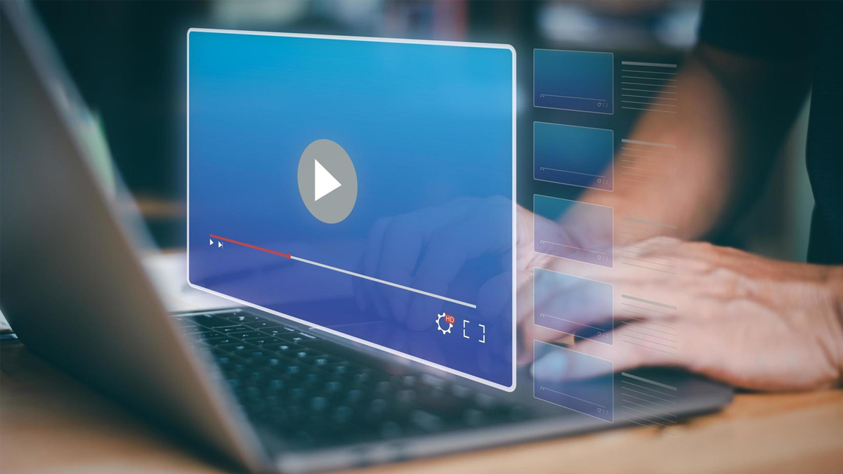 Hands typing on a laptop with a floating video player interface, showing a play button and a list of video thumbnails.