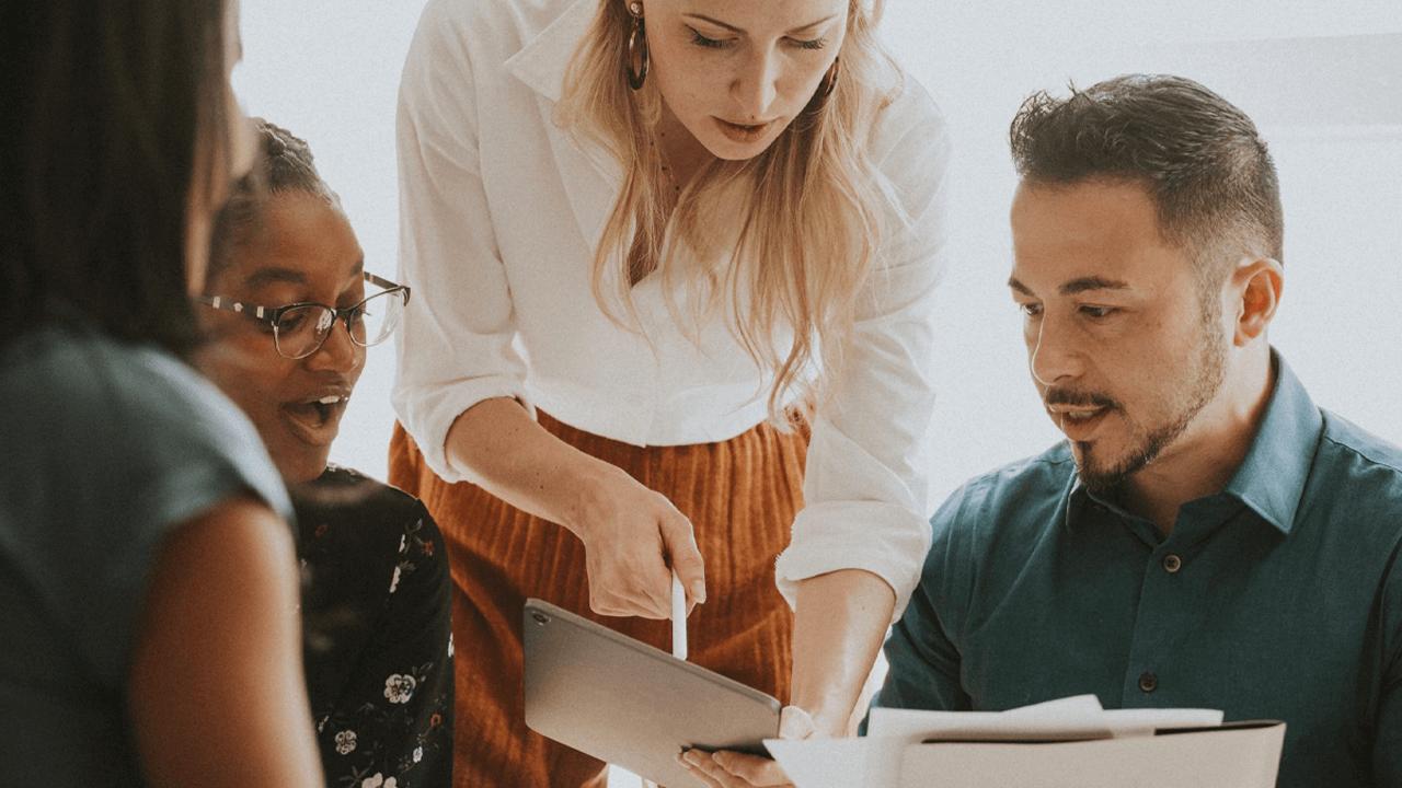Three diverse colleagues collaborating, looking at a tablet.