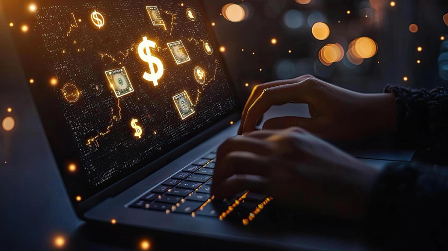 A person types on a laptop whose screen displays glowing financial symbols and charts, with bokeh lights in the background.