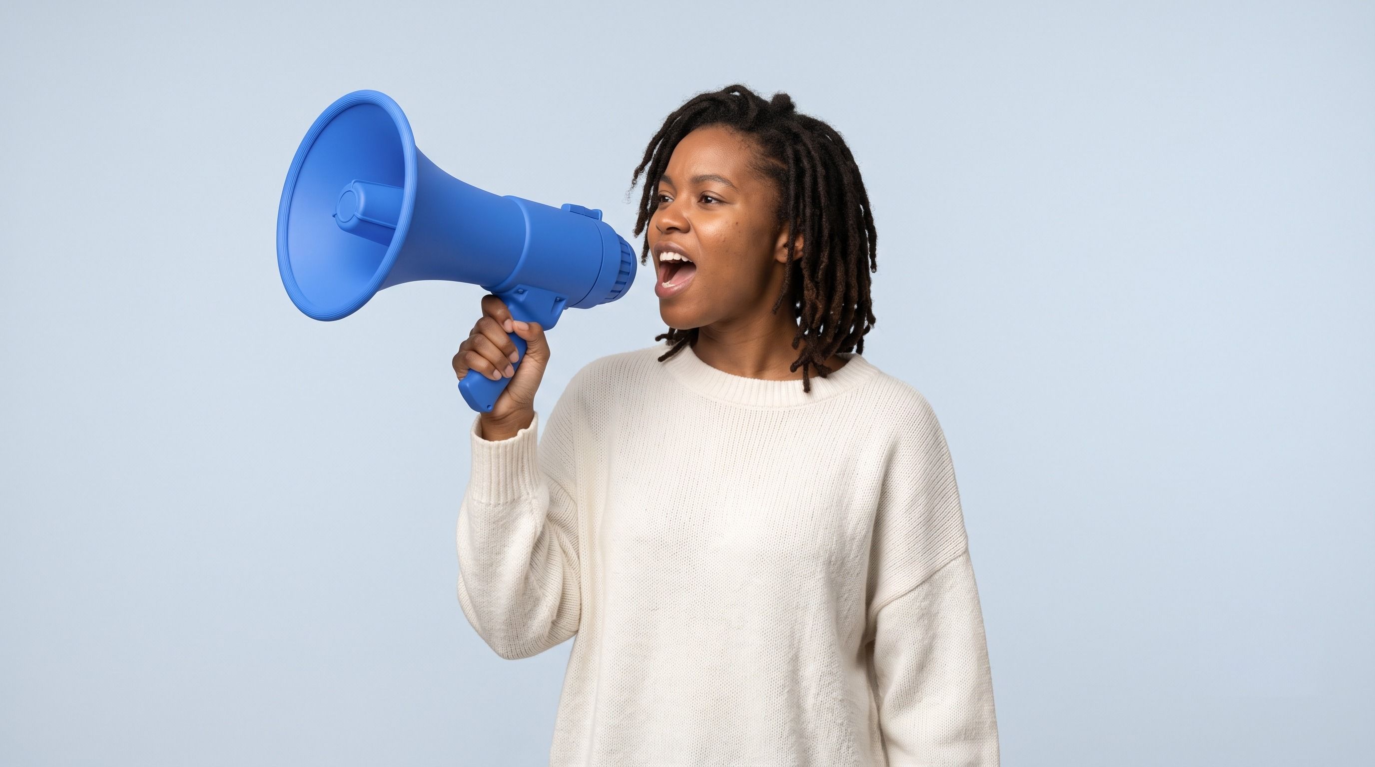 Woman with dreadlocks shouting into a blue megaphone.