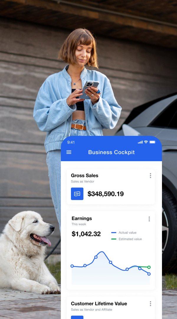 Uma mulher visualiza suas vendas e ganhos de negócios em um aplicativo móvel chamado 'Business Cockpit' enquanto um cachorro branco está deitado ao lado dela.