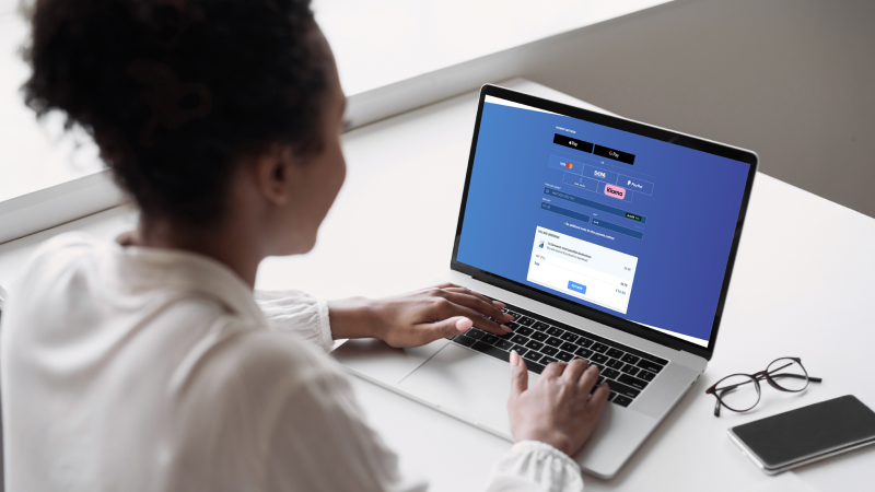Woman typing on a laptop displaying an online payment form.