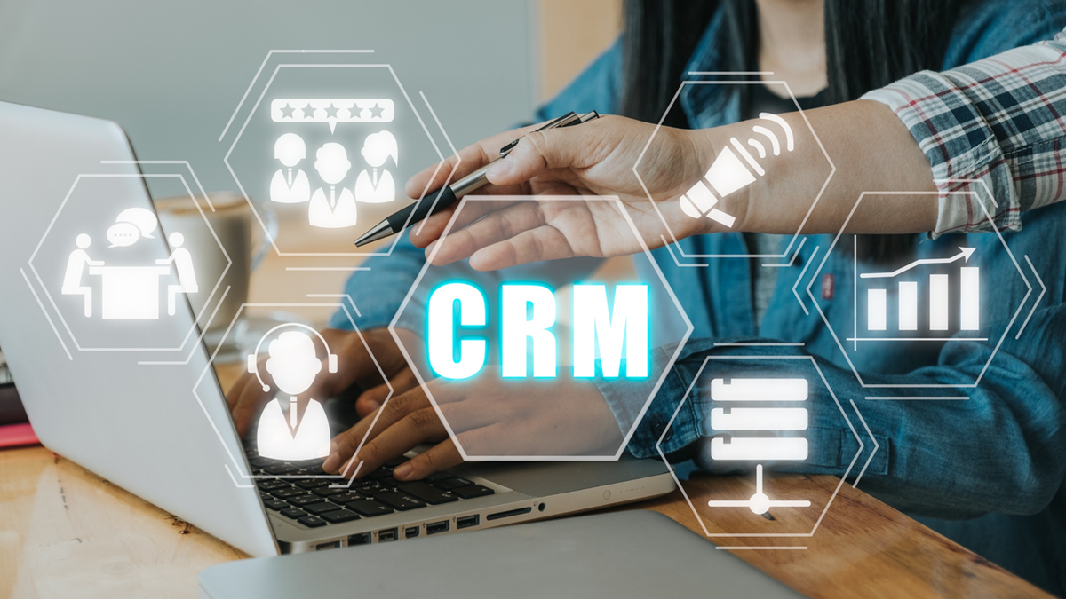 Conceptual image of CRM with a person on a laptop and floating icons.