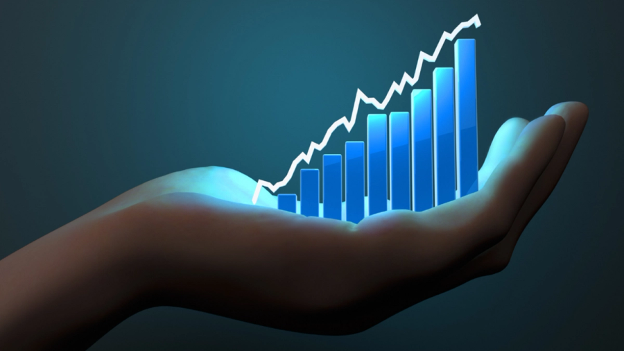 A hand holding a glowing blue bar graph with an upward-trending white line graph.