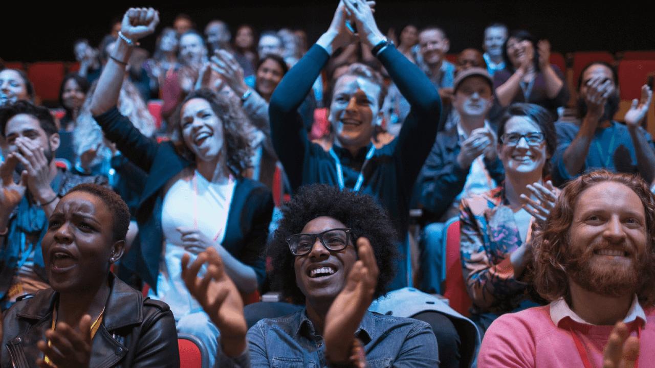 Enthusiastic and diverse audience clapping and cheering.