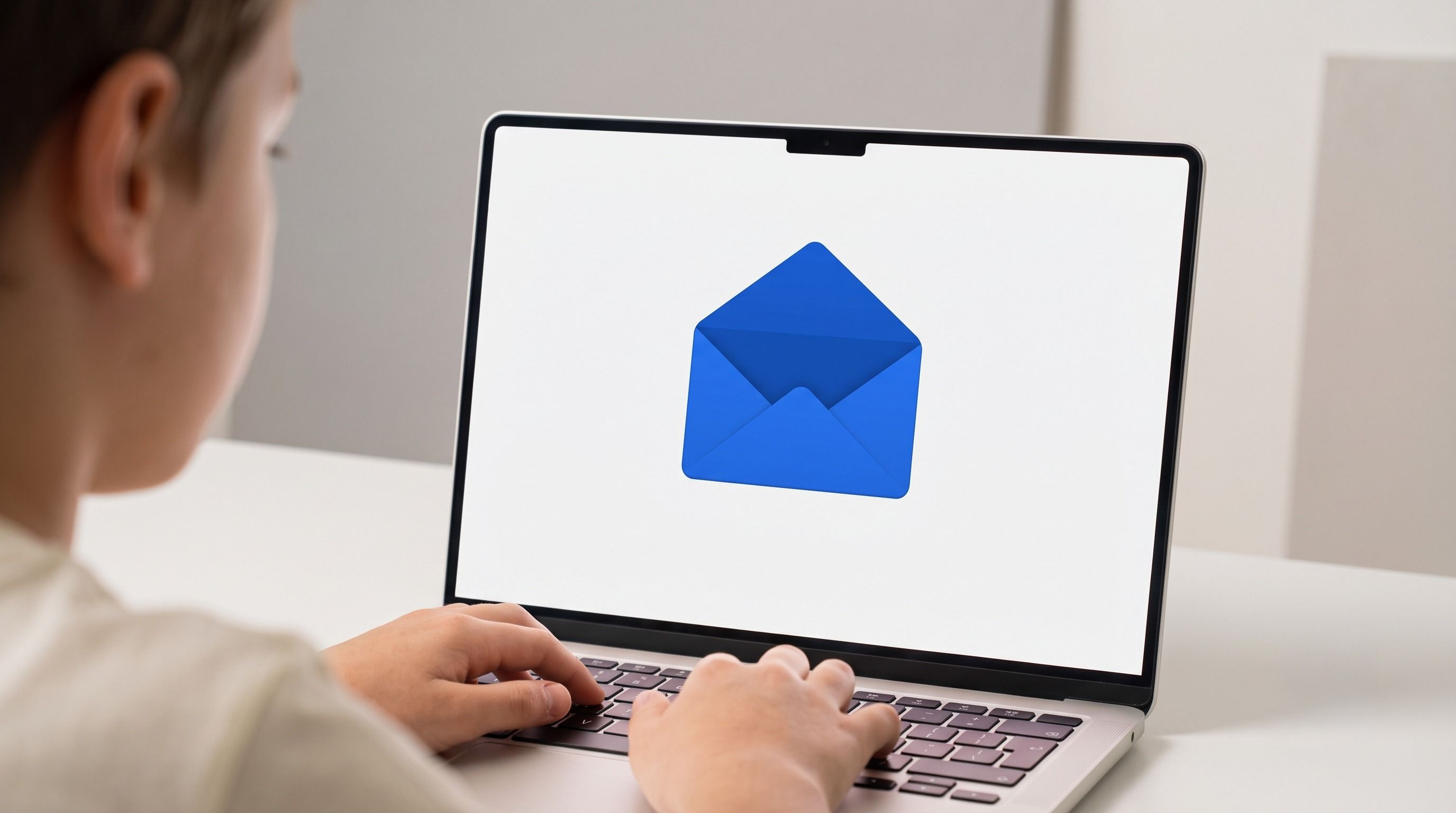 A person typing on a laptop displaying an open blue envelope icon.