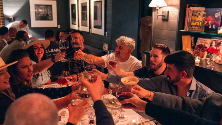 A group of people at a restaurant table raising their glasses in a toast.
